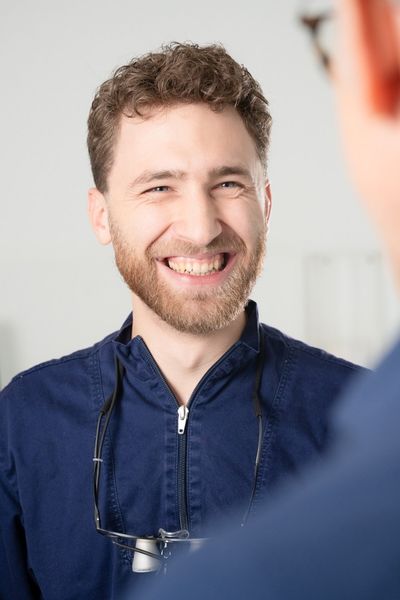 Zahnarzt von Smile & Care Göttingen im Gespräch mit einem lächelnden Patienten.