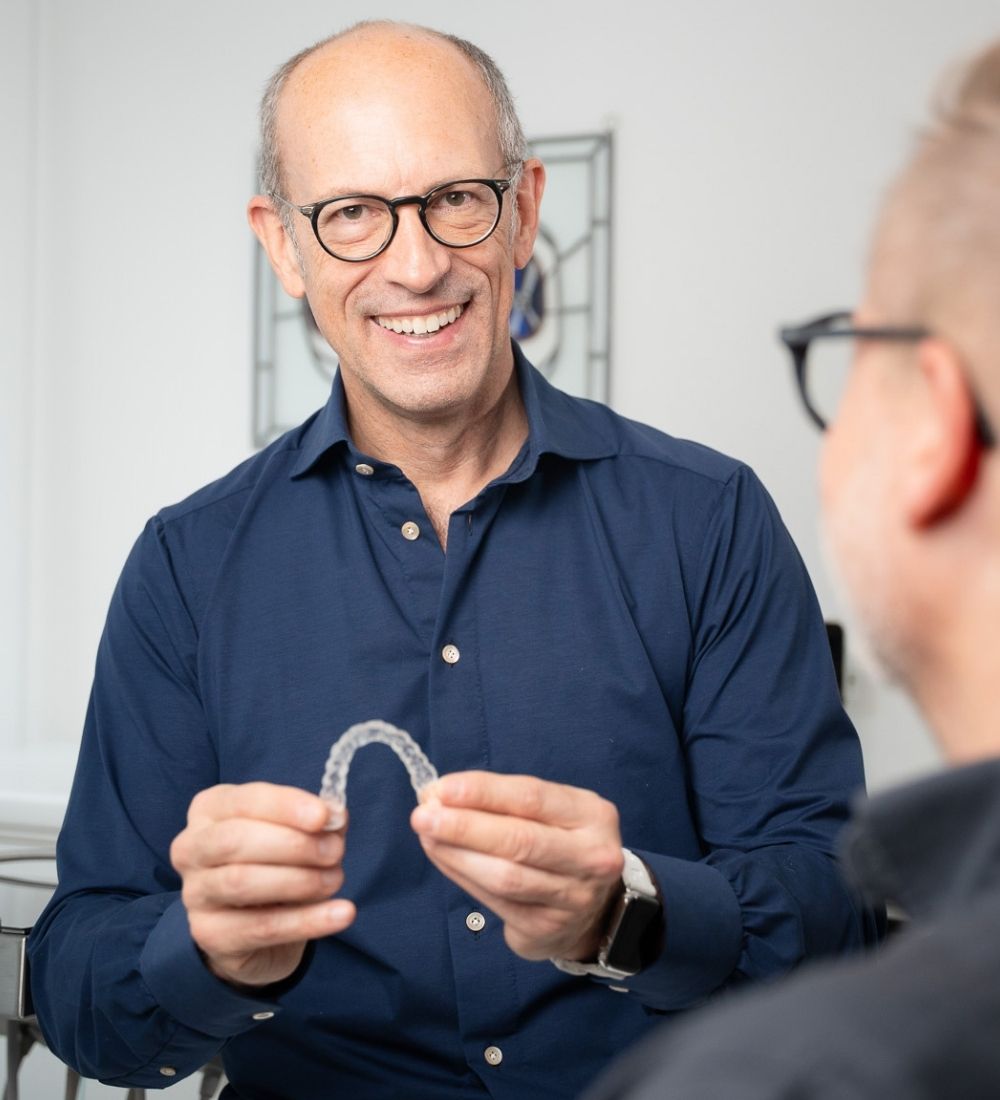 Dr. Torben Hennies zeigt eine transparente Aligner-Zahnschiene in seiner Praxis in Göttingen.