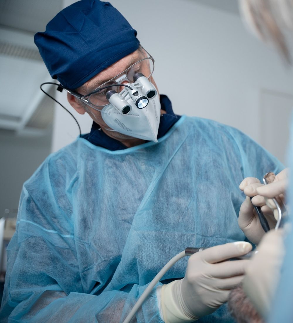 Dr. Hennies bei einer oralchirurgischen Behandlung in Göttingen – präzise Operation unter OP-Lupe.“