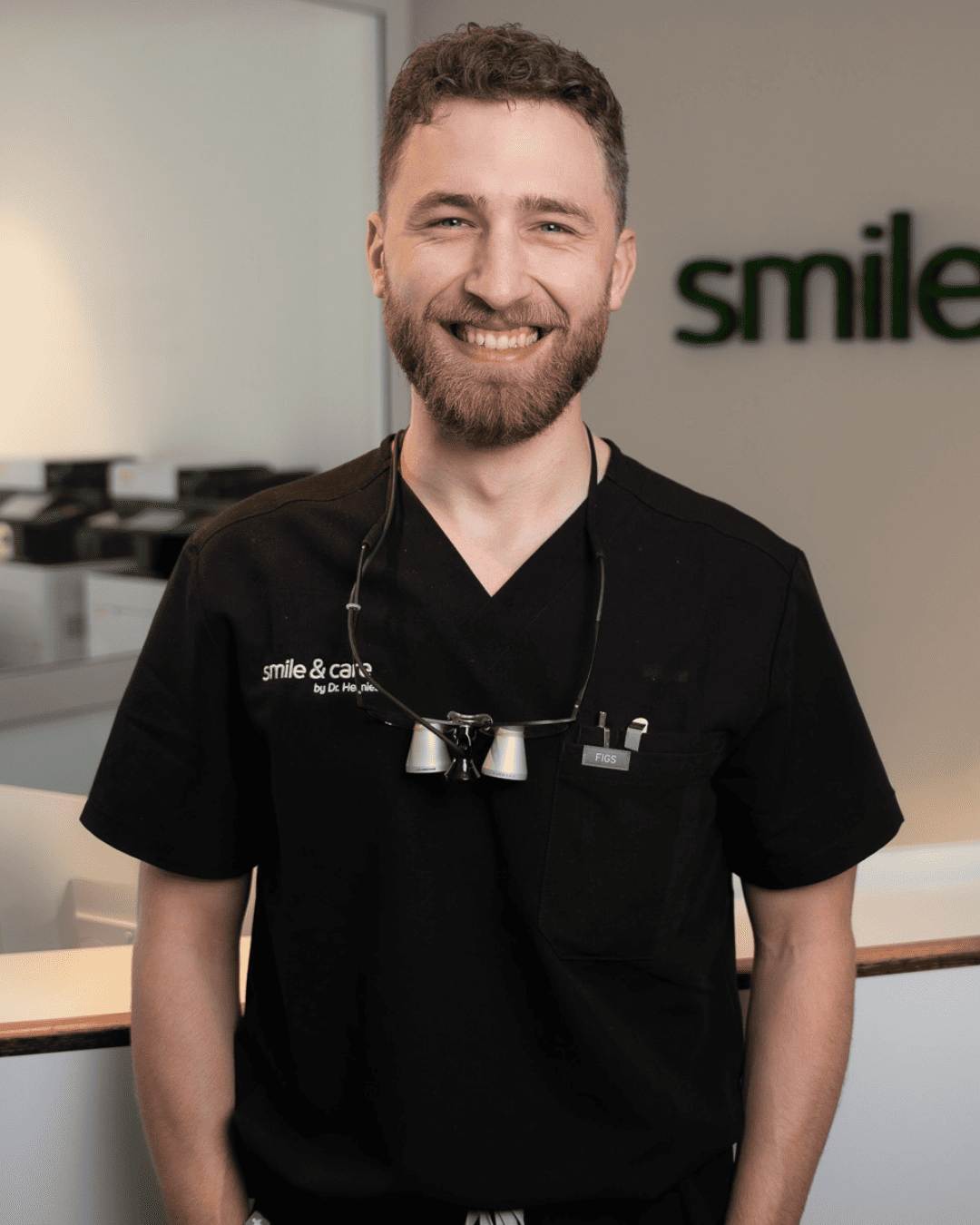 Lächelnder Behandler in schwarzer Praxiskleidung bei smile & care by Dr. Hennies in Göttingen.